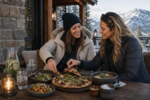 Adult friends share pizza and local dishes at a mountain restaurant